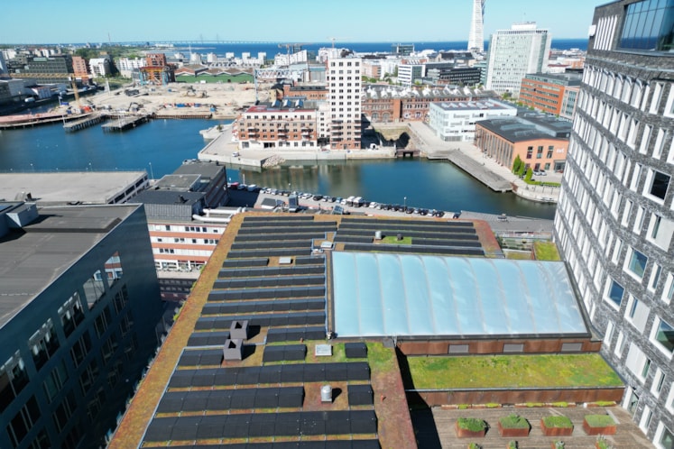 Solceller på Studios tak i Malmö och i bakgrunden ser man en siluett av Malmö, Turning torso och havet. 