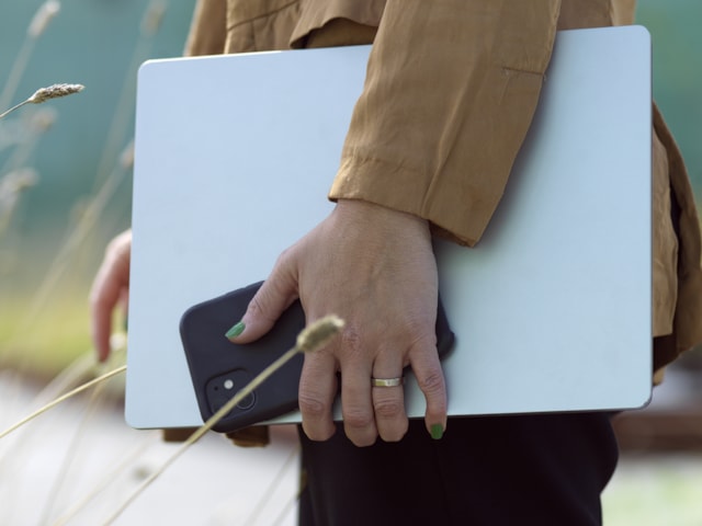 Person som håller en laptop och telefon i handen.