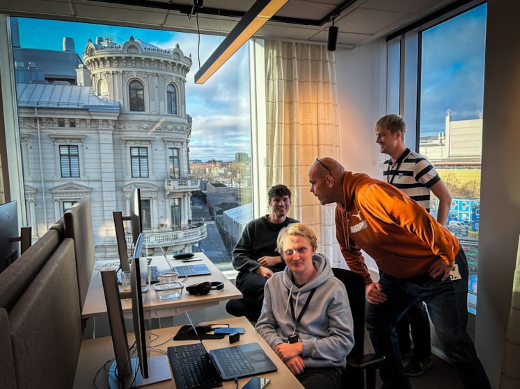 En grupp människor står runt ett skrivbord.